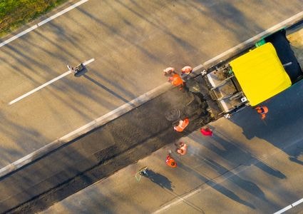 Road maintenance crew paving a road from above